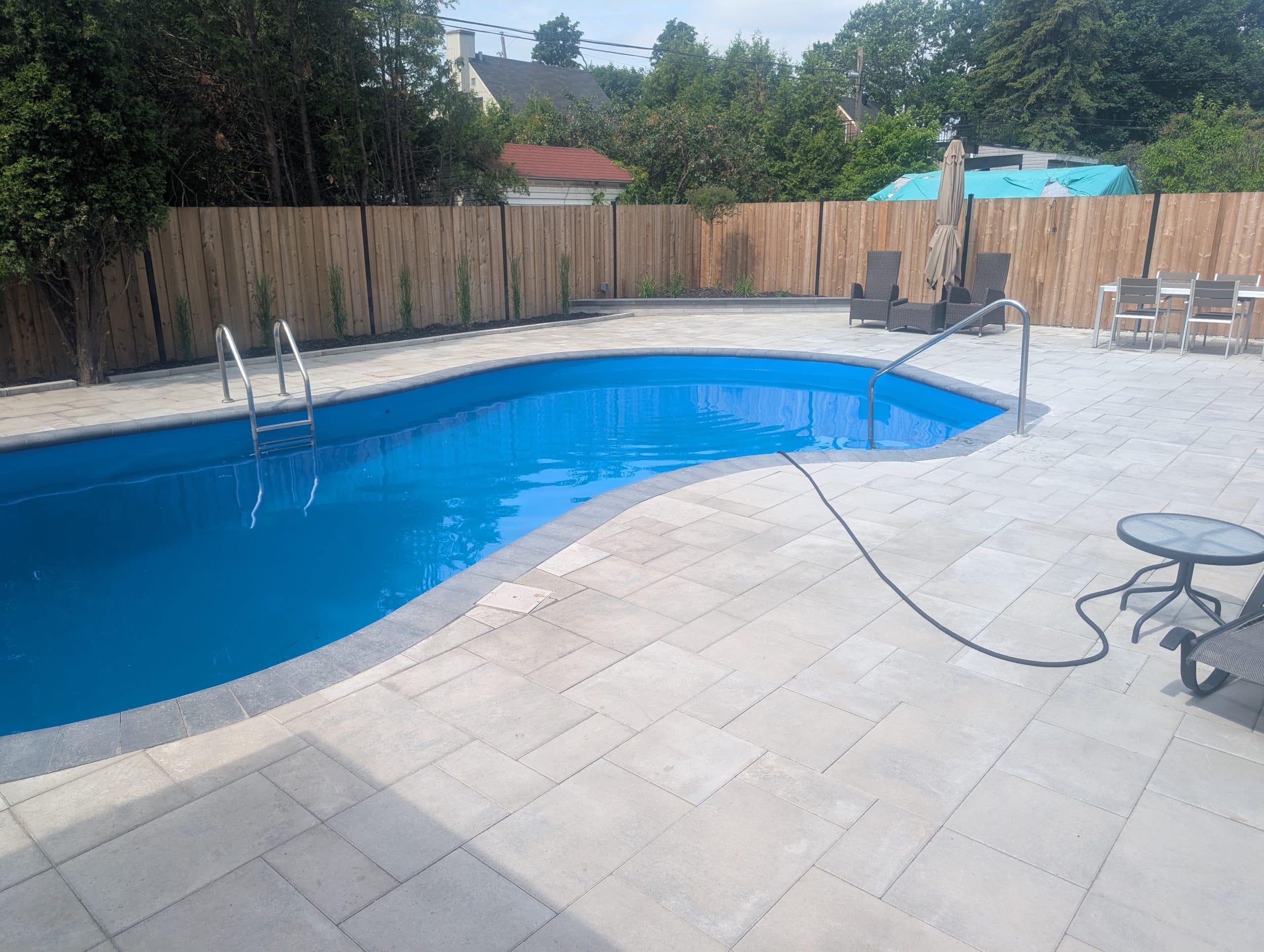 Terrasse en pavé uni beige autour d’une piscine creusée résidentielle à Laval
